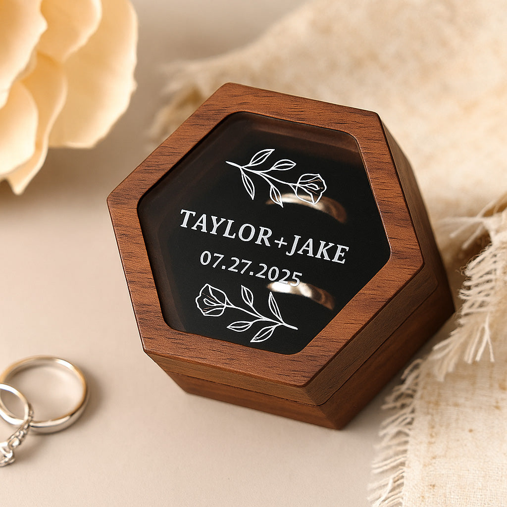 Wooden ring box with engraved names and date on a soft beige background