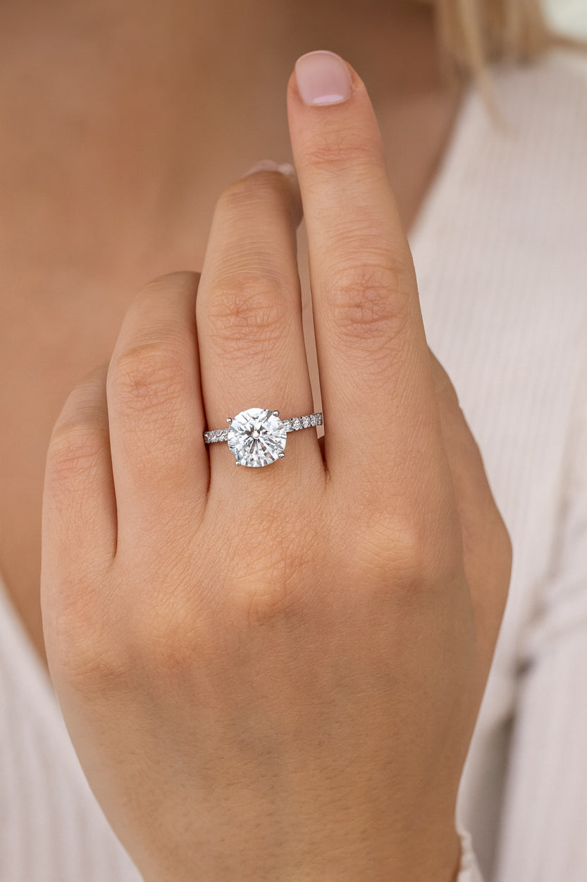 Round diamond engagement ring on hand shown in natural lighting