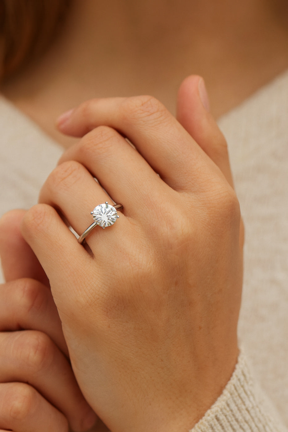 Round diamond solitaire engagement ring worn on hand