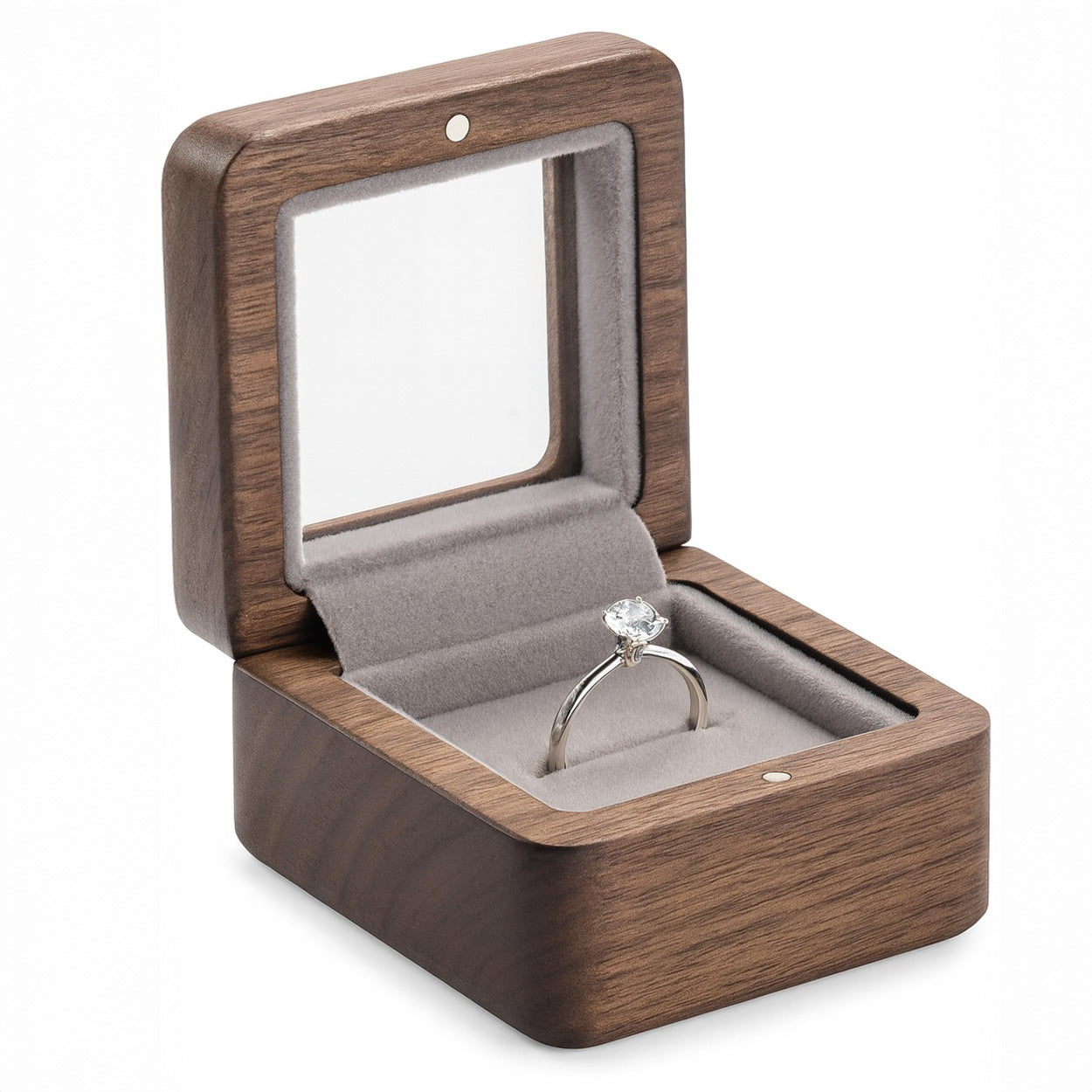 Open walnut wood ring box with glass lid and grey velvet interior holding engagement ring