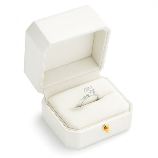 Open white luxury ring box with diamond button holding engagement ring